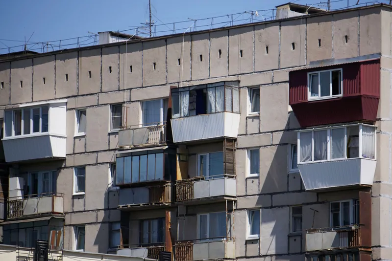 Фото: Остекление балконов в хрущевке разномастными деревянными, алюминиевыми и пластиковыми окнами на фасаде одного дома. © photogenica.ru 