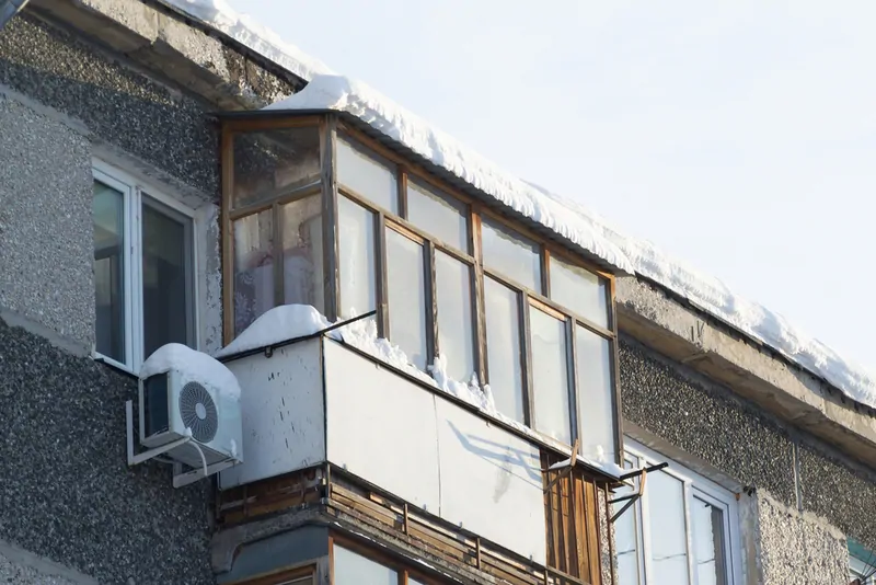 Фото: Незаконное остекление балкона на 5 этаже хрущевки. За состояние козырька отвечает владелец квартиры. Сбивать сосульки и чистить снег – его обязанность. © photogenica.ru 